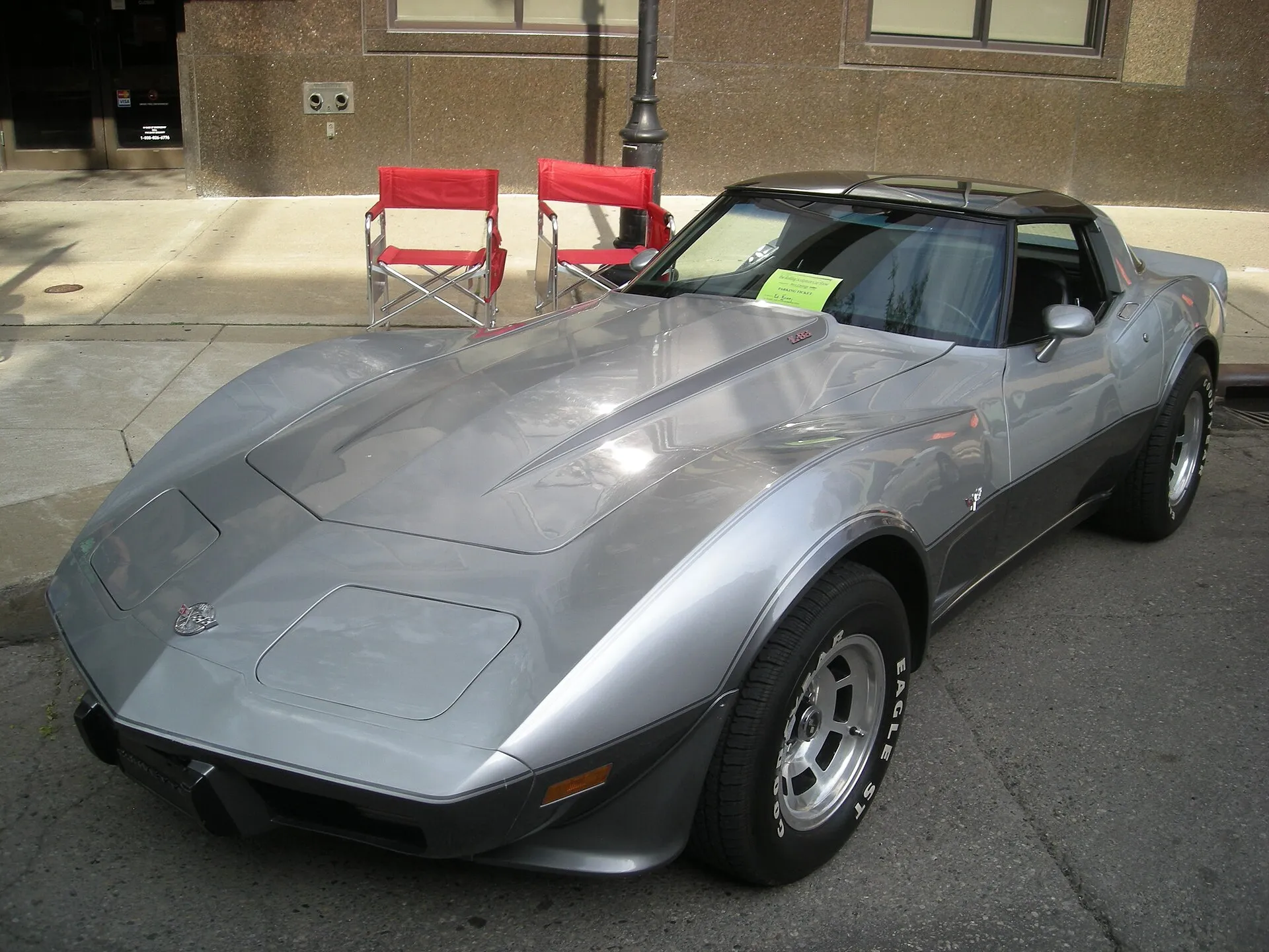 Silver and gray two-tone 1978 C3 Corvette coupe with T-tops, parked on a city street at a car show, seen from the front left corner.