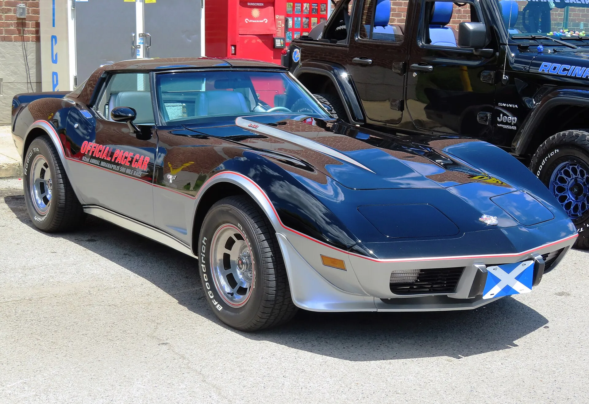 A black-over-silver 1978 Corvette Indianapolis 500 Pace Car Limited Edition with red pinstripes and door lettering, seen from the front right in a parking lot.