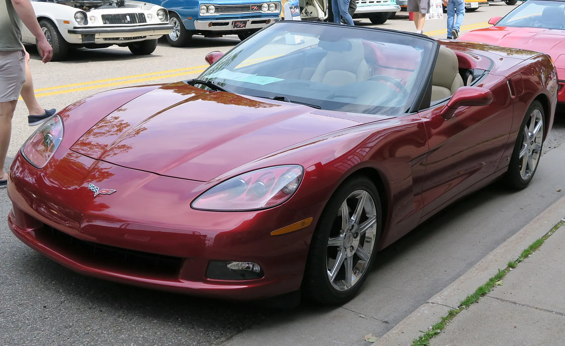 Red 2008 Chevrolet Corvette convertible with the top down, parked at a street car show