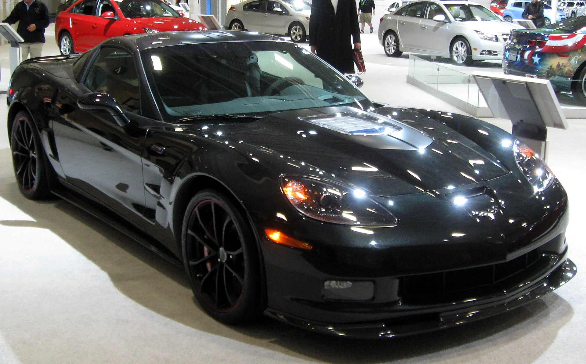 Black 2012 Chevrolet Corvette ZR1 on an auto show floor, with a clear window in the hood