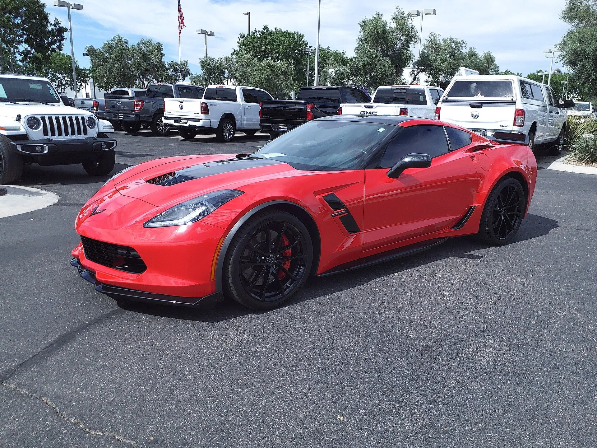 Red 2019 Chevrolet Corvette Grand Sport coupe with black wheels and red brake calipers on a dealer lot.