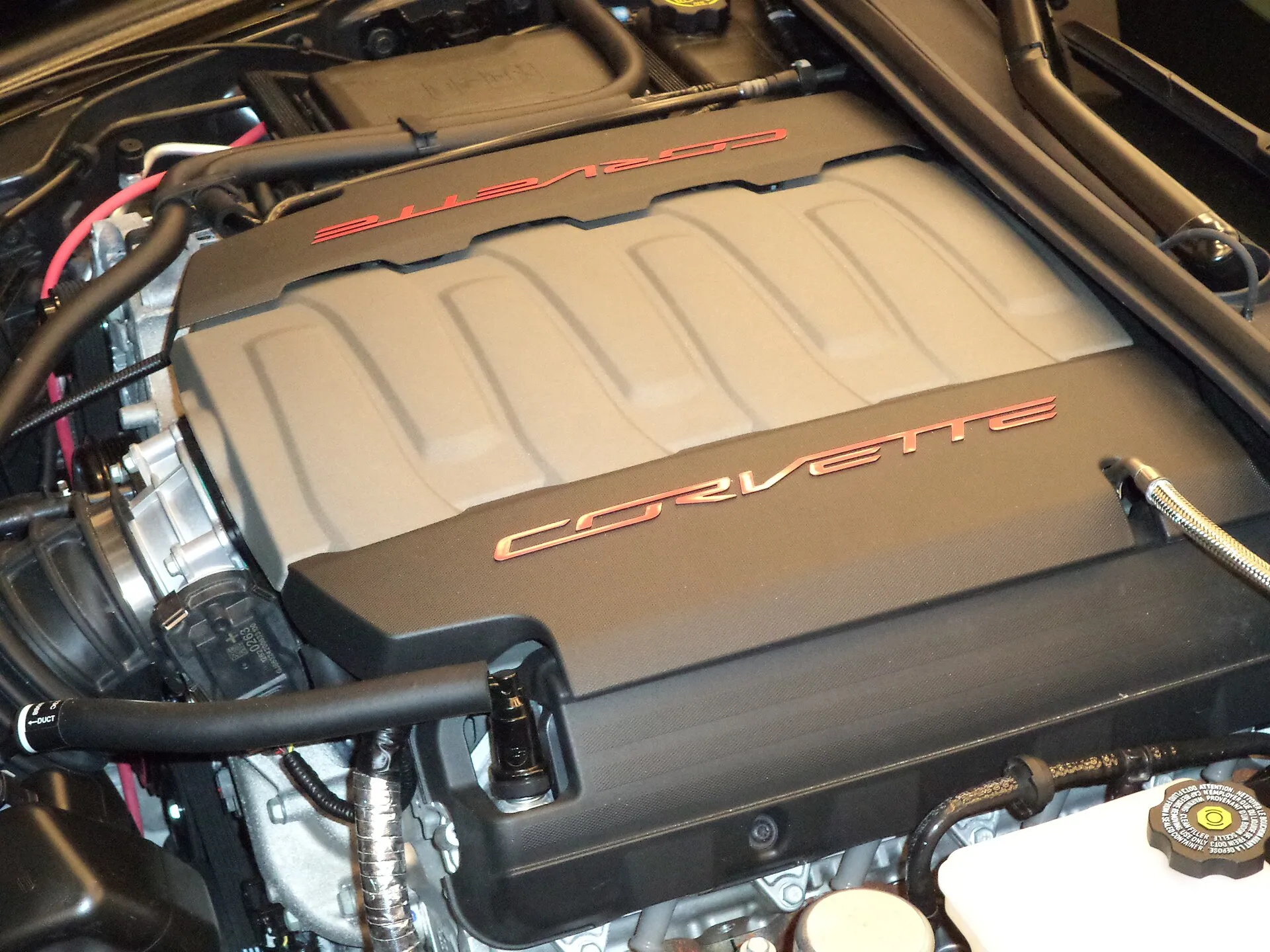 The top of a C7 Corvette Stingray's LT1 V8 under its black engine cover with red Corvette lettering.