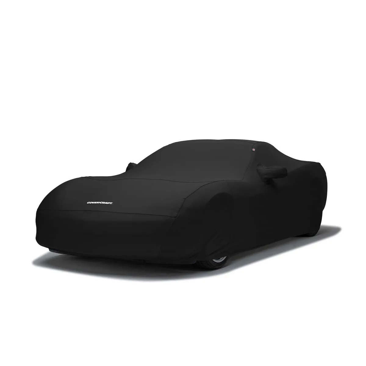 A black Covercraft Form-Fit stretch cover fitted snugly over a low sports car, with mirror pockets and the Covercraft name on the nose.