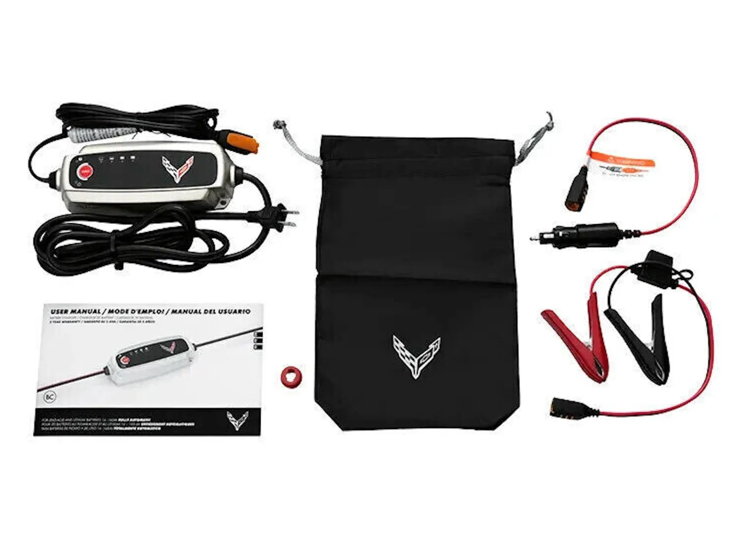GM's Corvette battery charger kit laid out flat: the silver charger with a crossed-flags logo and its cord, a black storage pouch, the user manual, an outlet plug lead and a clamp lead.